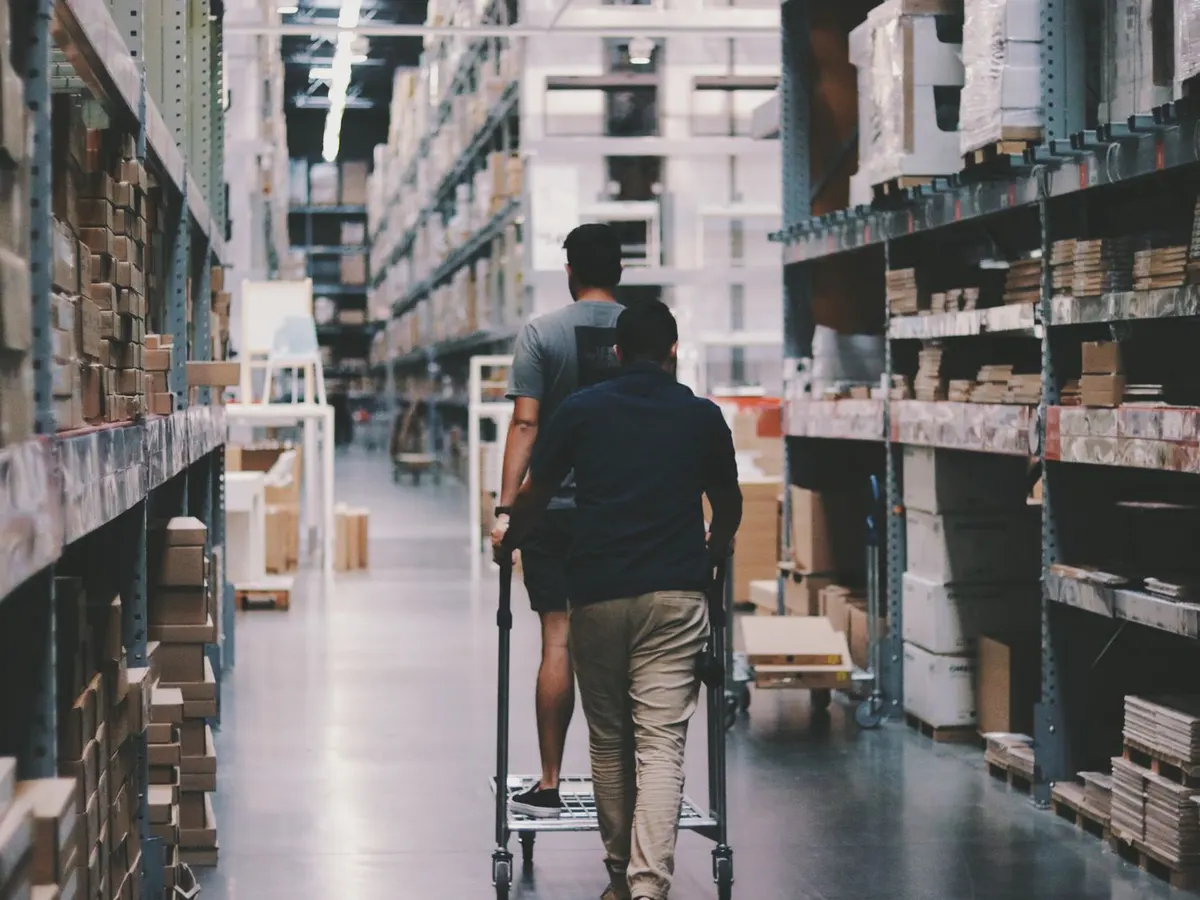 Open buying guide on a tablet beside a lithium electric pallet truck, a zinc plated cash and carry trolley and a platform scale